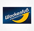 Weißer Schriftzug „Wockenfuß Hörakustik“ mit gelbem Halbkreis auf dunkelblauem Hintergrund.