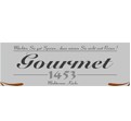 Graues Schild mit schwarzem Schriftzug Gourmet 1453 Willkommen, Ende und dekorativen braunen Linien an den Seiten.