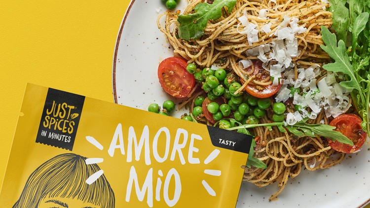 Ein Teller mit Spaghetti, Erbsen, Rucola, Cherrytomaten und Käse, vorne eine gelbe Verpackung mit der Aufschrift „JUST SPICES AMORE MIO“.