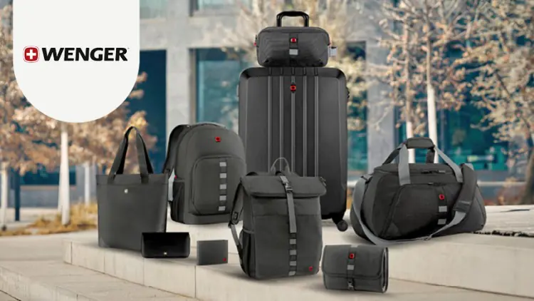 Verschiedene schwarze und graue Taschen und Koffer von WENGER stehen auf einer steinernen Fläche, im Hintergrund sind Bäume.