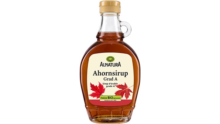 Glasflasche mit braunem Ahornsirup, gelbem Deckel und Etikett von Alnatura, roten Ahornblättern und „Ahornsirup Grad A“-Text.