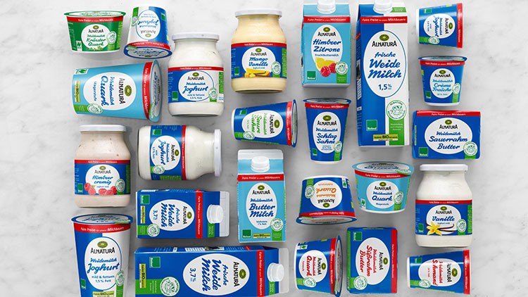 Mehrere Alnatura-Molkereiprodukte wie Joghurt, Butter und Milch mit blauem Design liegen auf hellem Untergrund.