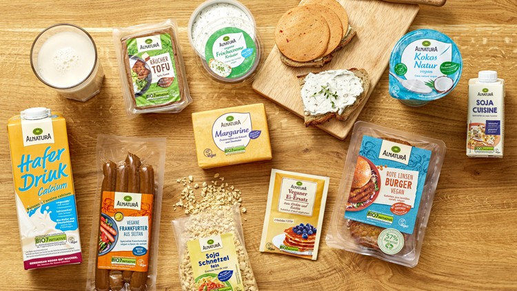Verschiedene Bio-Lebensmittel der Marke Alnatura, darunter Haferdrink, Tofu, Brotaufstriche, Margarine, Würstchen und Sojasahne.