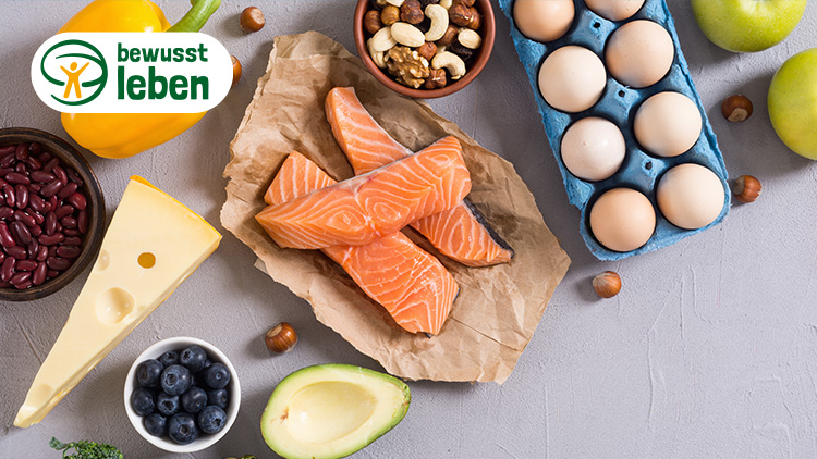 Verschiedene Lebensmittel wie Lachs, gelbe Paprika, Eier, Nüsse, Käse, rote Bohnen und Äpfel mit dem Logo „bewusst leben“.