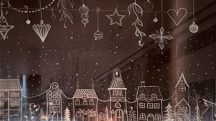 Auf einem Fenster sind weiße Zeichnungen von Häusern, Bäumen, Sternen und Weihnachtsdekoration, umrahmt von kleinen Punkten.