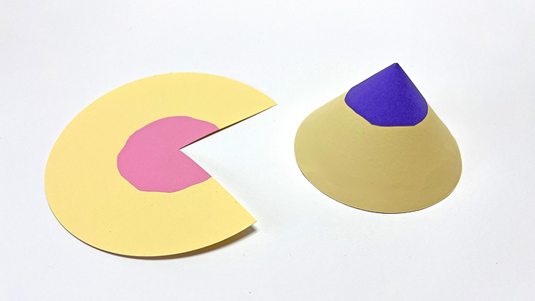 Gelber Papierkreis mit rosa Fläche und Ausschnitt neben einem gelben Papierkegel mit lila Spitze auf weißem Hintergrund.
