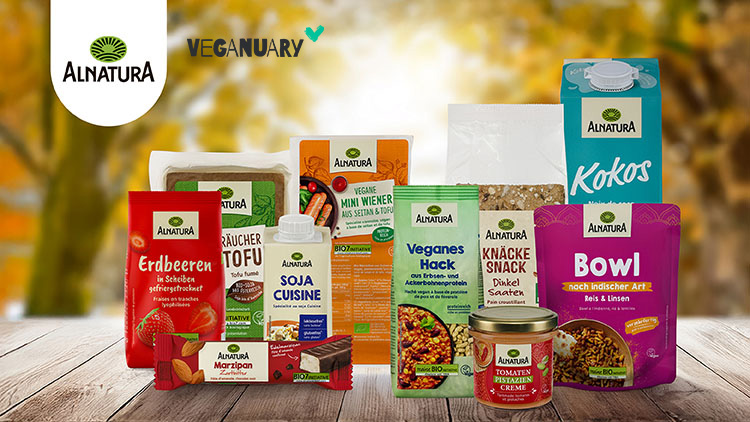 Produkte von Alnatura, darunter Snacks, Tofu, Pflanzenmilch und Brotaufstrich, vor einem herbstlichen Hintergrund mit Bäumen.