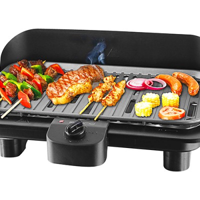 Ein Tischgrill mit Gemüse-Spießen, Fleisch-Spießen, Würstchen, Maiskolben, Tomatenscheiben und Zwiebelringen auf der Grillfläche.