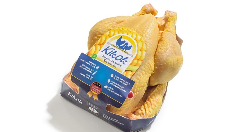Verpacktes, ganzes Kikok-Hähnchen mit gelber Haut, Etikett mit Maiskolben, Text zu Tierwohl und ohne Gentechnik.