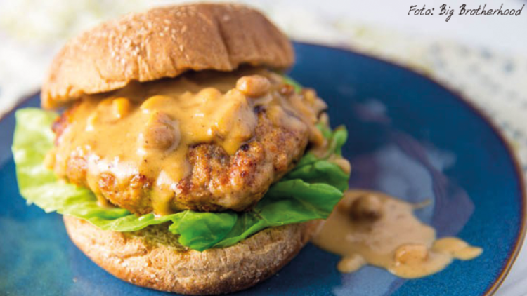 Burger mit Brötchen, Salatblatt, Patty und cremiger Sauce mit Pilzstücken auf einem blauen Teller.