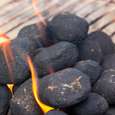 Schwarze Grillbriketts mit rot-gelben Flammen auf einem Grillrost.