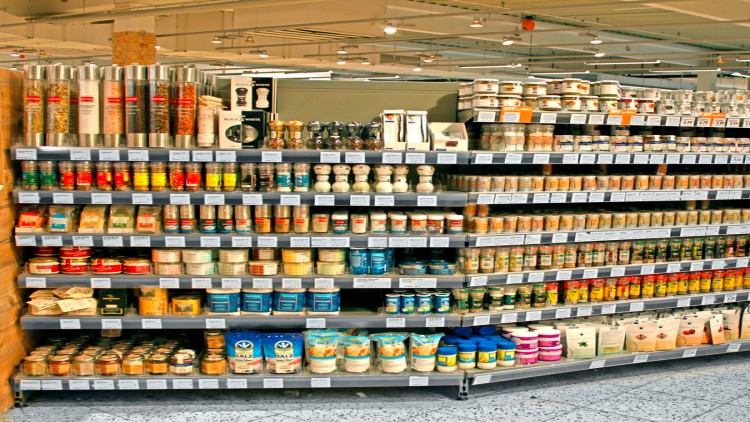 Regal mit Gewürzen, Salzen, Pfeffermühlen und Teedosierungen in verschiedenen Verpackungen und Farben in einem GLOBUS-Markt.