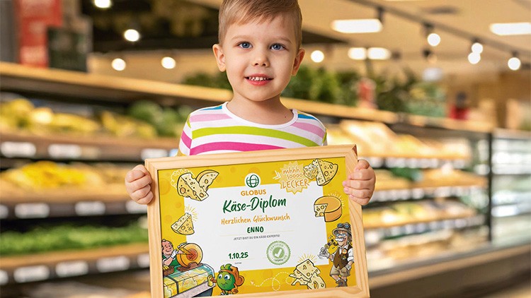 Kind hält gerahmtes GLOBUS Käse-Diplom, Hintergrund zeigt eine gut beleuchtete Lebensmittelabteilung mit Käseprodukten.