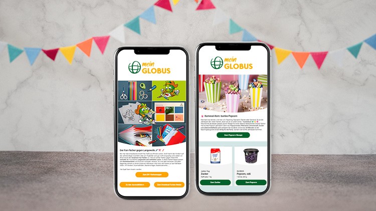 Zwei Smartphones zeigen Infos zu mein GLOBUS mit Globini, Bastelideen und Popcorn vor grauem Hintergrund mit bunter Wimpelgirlande.