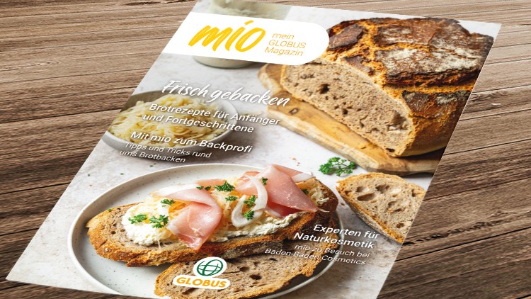 Broschüre „mio – mein GLOBUS Magazin“ mit Brot, Schinken und Frischkäse auf Holzuntergrund, Texte zu Brotbacken und Naturkosmetik.