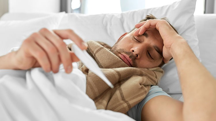 Mann mit Fieber im Bett
