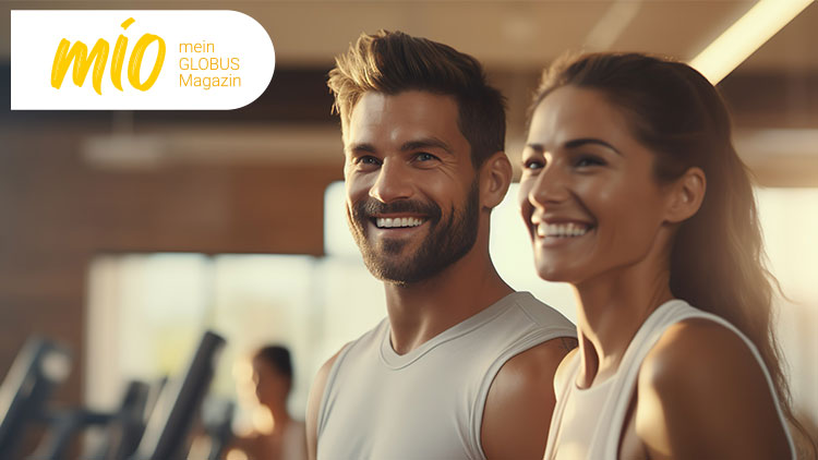 Zwei Personen in Sportkleidung stehen in einem Fitnessstudio, oben links steht „mio mein GLOBUS Magazin“ auf weißem Hintergrund.