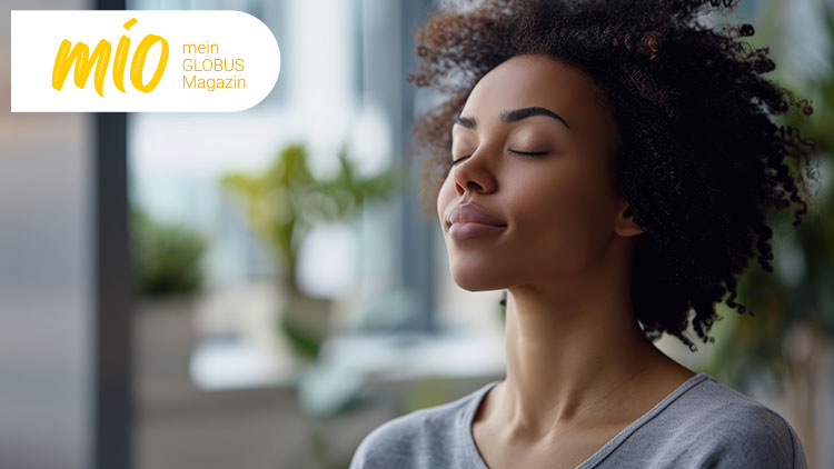 Das mio mein GLOBUS Magazin-Logo in Gelb und Weiß, im Hintergrund verschwommene Pflanzen und Fensterfront.
