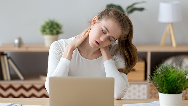 Frau mit Nackenschmerzen am Laptop