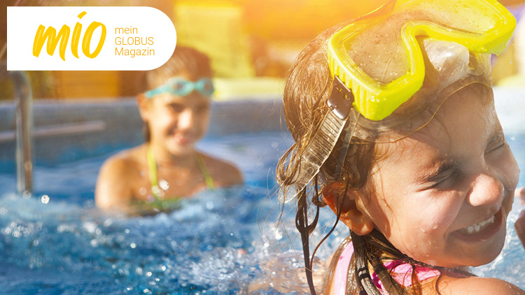 Ein Kind mit gelber Taucherbrille und nassen Haaren im Wasser, oben links das mio mein GLOBUS Magazin-Logo.