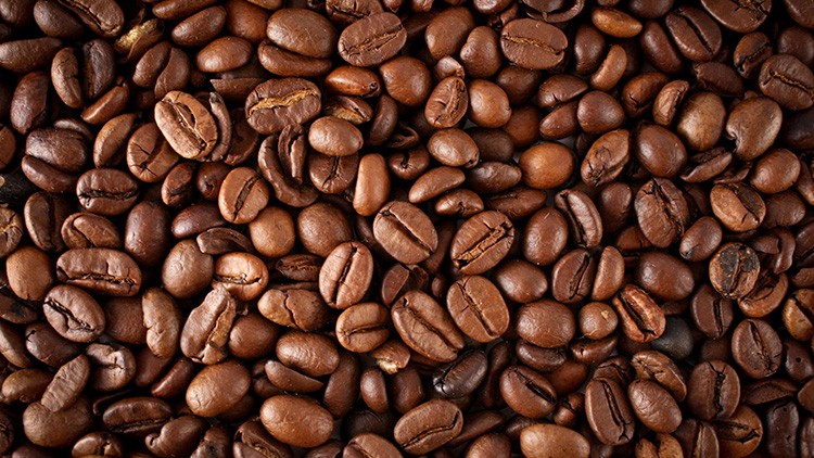 Nahaufnahme von gerösteten Kaffeebohnen in verschiedenen Brauntönen, die dicht nebeneinander liegen.