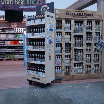 Regal mit Flaschen der Insel-Brauerei und weitere Getränkereihen in einer Craft Beer Arena mit Ziegelwand-Optik.
