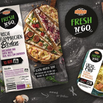 GLOBUS Fresh N‘ Go Produkte wie Flammkuchenböden, Pasta mit Soße, Sandwich, gefüllte Teigtaschen und Smoothie auf dunklem Hintergrund.