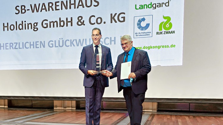 Zwei Männer in Anzügen stehen vor einer Leinwand mit der Aufschrift GLOBUS SB-WARENHAUS Holding GmbH & Co. KG.