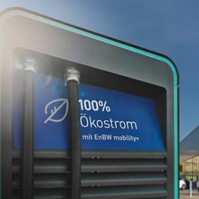 Eine Ladesäule mit der Aufschrift „100 % Ökostrom mit EnBW mobility+“ steht vor einem GLOBUS Markt mit Eingang und Logo.
