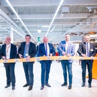 Mehrere Personen schneiden ein gelbes GLOBUS-Band durch, Ballons in Orange und Weiß stehen im Hintergrund.