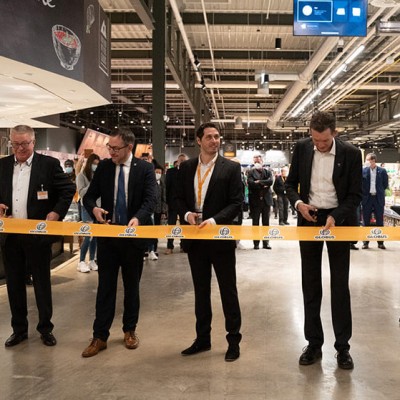 Sechs Personen schneiden ein gelbes Band mit GLOBUS-Logo vor Publikum in einem Marktbereich durch.