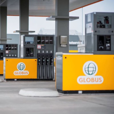 Mehrere gelb-graue Zapfsäulen mit GLOBUS-Logo stehen überdacht in einer modernen Tankstelle.
