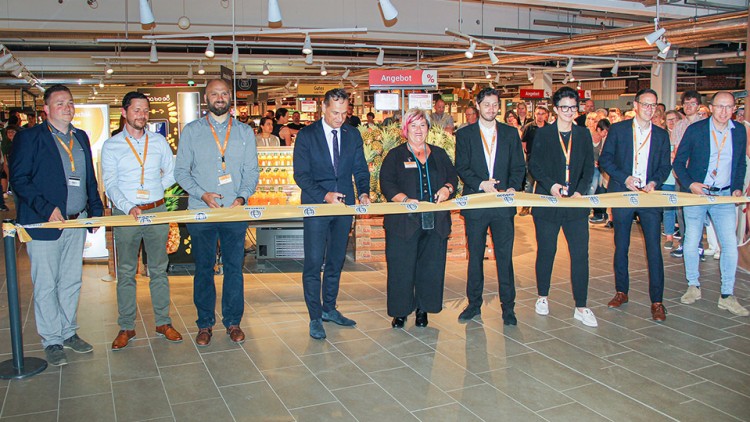 Mehrere Personen schneiden ein GLOBUS-Band durch, im Hintergrund sind Regale und der Schriftzug „Angebot“ sichtbar.