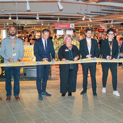 Mehrere Personen schneiden ein GLOBUS-Band durch, im Hintergrund sind Regale und der Schriftzug „Angebot“ sichtbar.