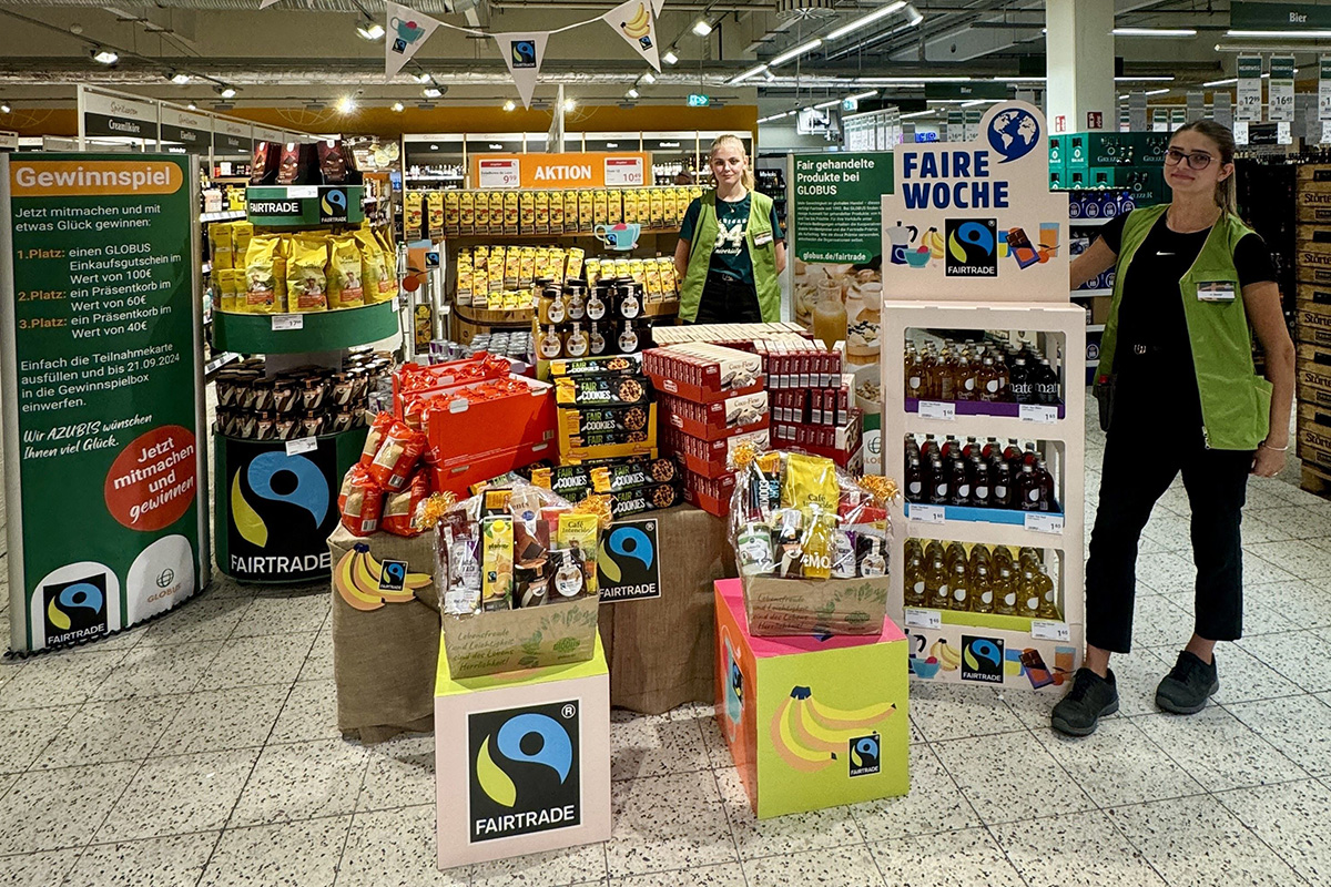 Ausstellung von fair gehandelten Produkten mit FAIRTRADE-Logo, Gewinnspiel-Hinweis und Tischaufbauten in einem GLOBUS-Markt.