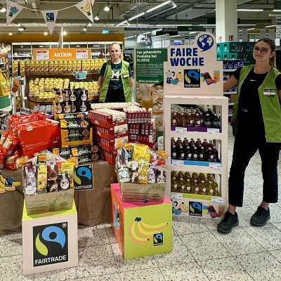 Ausstellung von fair gehandelten Produkten mit FAIRTRADE-Logo, Gewinnspiel-Hinweis und Tischaufbauten in einem GLOBUS-Markt.
