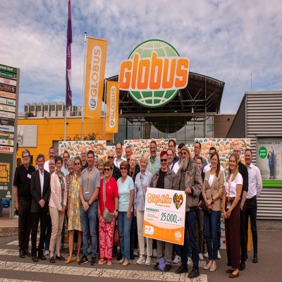 Mehrere Personen stehen vor dem GLOBUS-Markt, halten einen großen Spendenscheck mit der Aufschrift „Tafel-Aktion, 25.000,- €“.