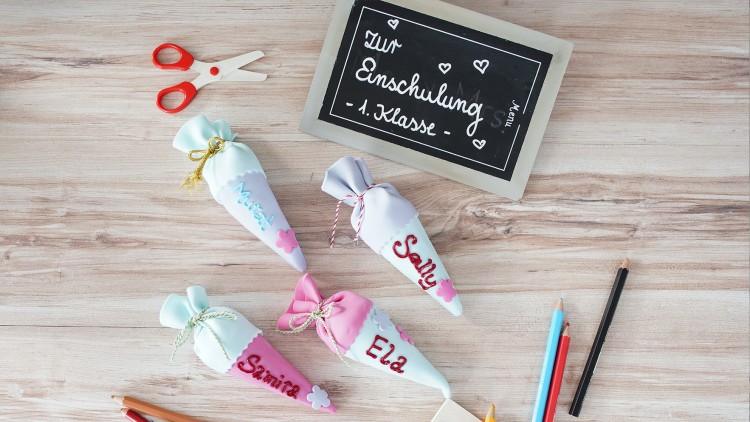 Vier kleine bunte Schultüten und eine Tafel mit der Aufschrift \