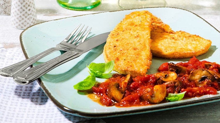 Auf einem hellblauen Teller liegen zwei Kartoffelpuffer mit Tomatensoße, Champignons und Basilikum, daneben Besteck.
