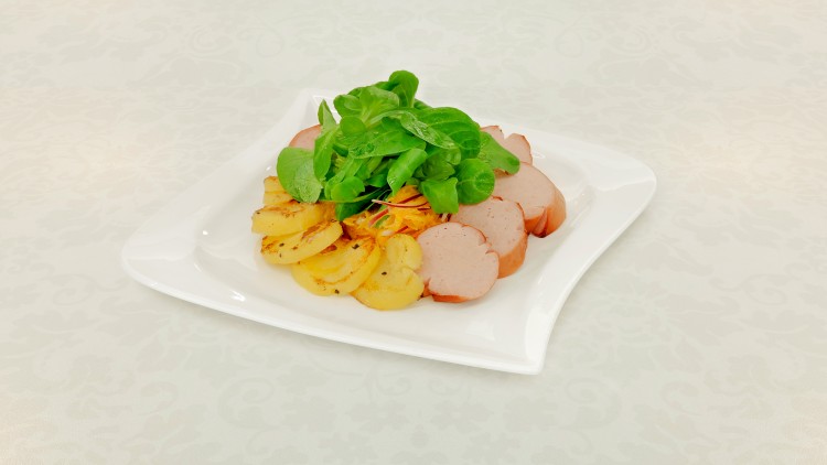 Ein weißer Teller mit Kartoffelscheiben, Wurstscheiben, Salat und fein geraspeltem Gemüse auf einer hell gemusterten Tischdecke.