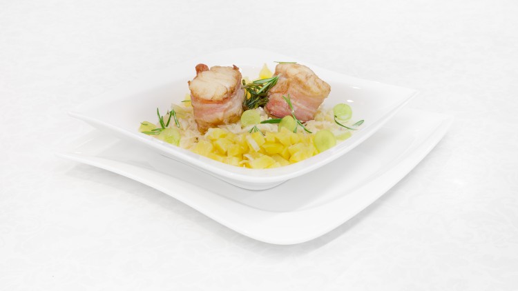Zwei Fleischröllchen mit Speck auf Sauerkraut und gewürfelten Kartoffeln, garniert mit Kräutern und Traubenscheiben.