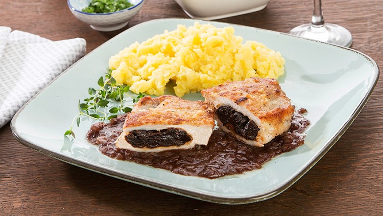 Gefüllte Fleischstücke mit Sauce und Kartoffelpüree auf einem Teller, daneben ein Glas Rotwein und kleine Schalen.