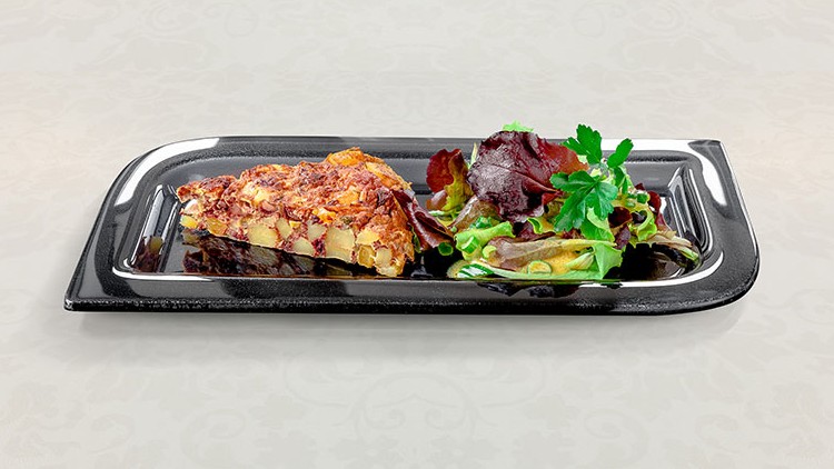 Ein Stück Kartoffelauflauf und gemischter Blattsalat mit Kräutern auf einem schwarzen rechteckigen Teller.