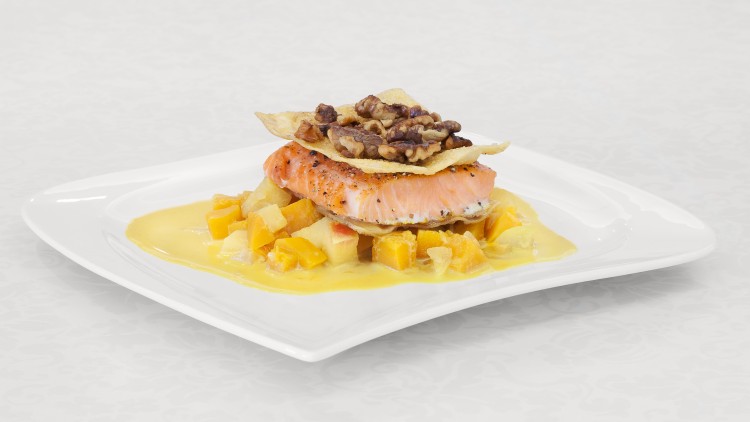 Gebratenes Lachsfilet auf Würfeln von gelbem Gemüse mit heller Sauce, dekoriert mit Walnüssen und knusprigen Chips.
