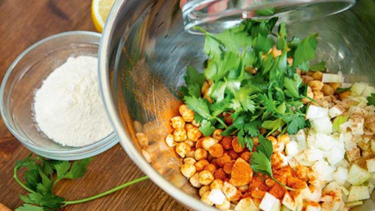 In einer Schüssel sind Gewürze, frische Petersilie, Zwiebelstücke und Croutons, daneben eine Schale mit Mehl.