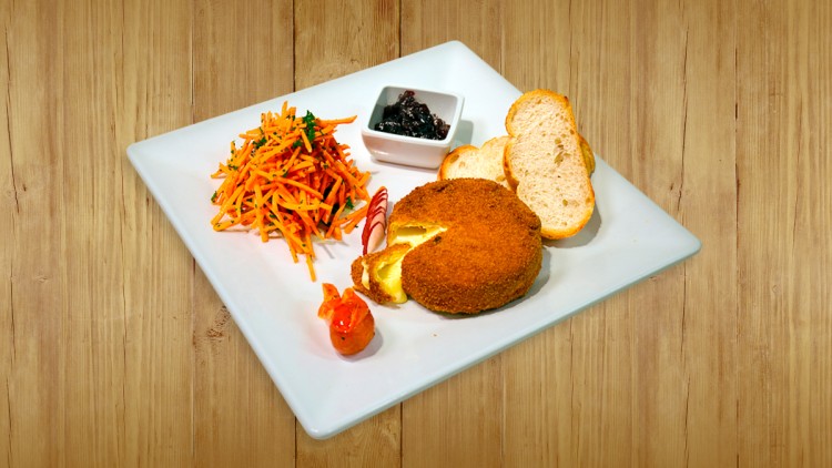 Panierter und geschmolzener Käse mit Karottensalat, Preiselbeersoße, Baguettescheiben und Dekoration auf quadratischem Teller.