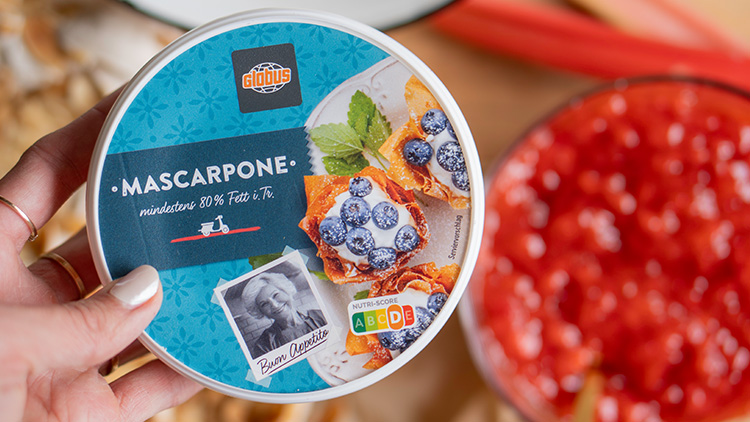 Runder Mascarpone-Becher von GLOBUS mit einem Bild von Gebäck mit Blaubeeren und Minze, dazu Nutri-Score A bis E.