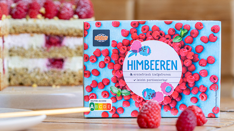 Verpackung von GLOBUS Himbeeren mit weißer Schrift auf blauem Hintergrund, daneben frische Himbeeren und eine Torte.