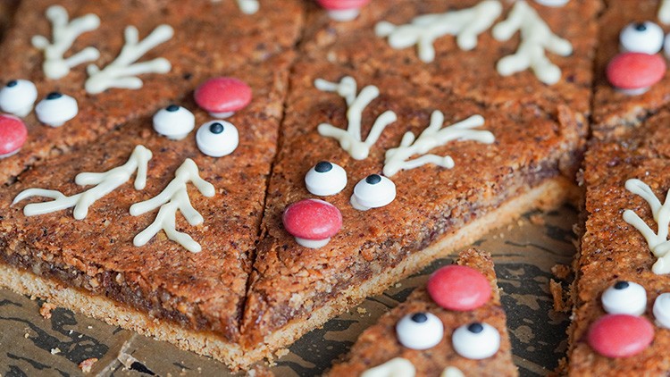 Braune Gebäckstücke in Dreiecksform, dekoriert mit weißen Augen aus Zuckerguss, roten Nasen und weißen Geweihen.