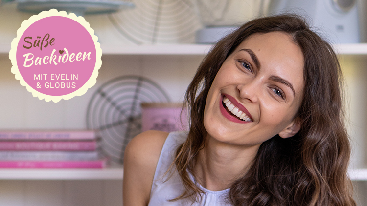 Ein Regal mit rosa Backbüchern, Kuchengittern und einer pinken Dose, weitere Küchenutensilien und der Schriftzug „Süße Backideen mit Evelin & GLOBUS“.